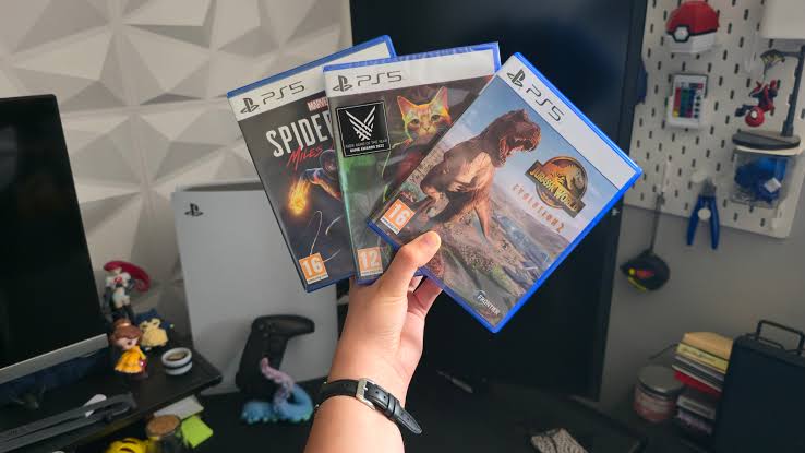 PlayStation 5 lemezek és egy konzol a háttérben elhomályosítva